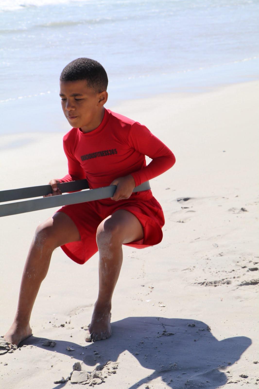 Athlete in a band squat on the sand