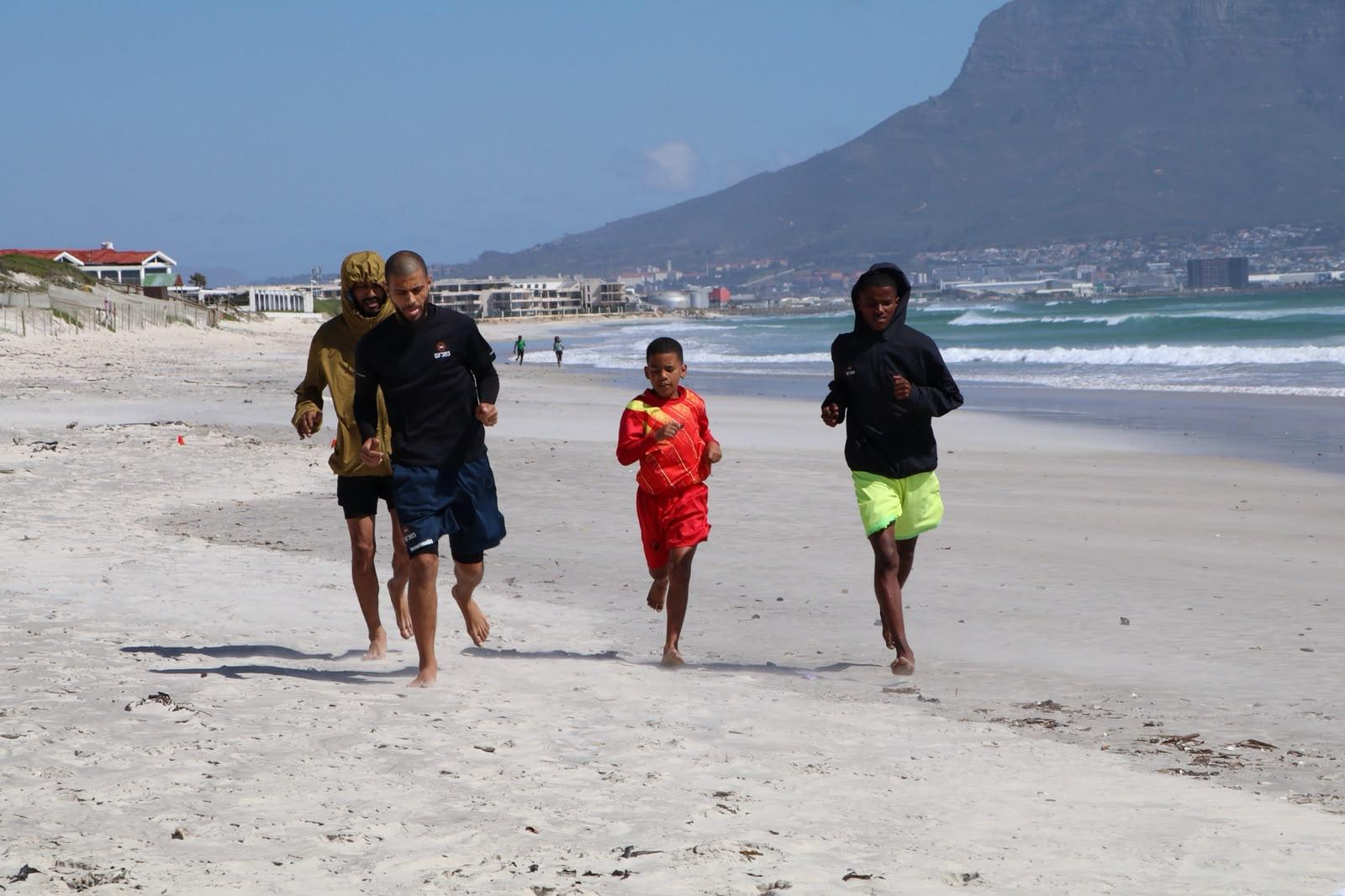 Coach and athletes running together on the beach