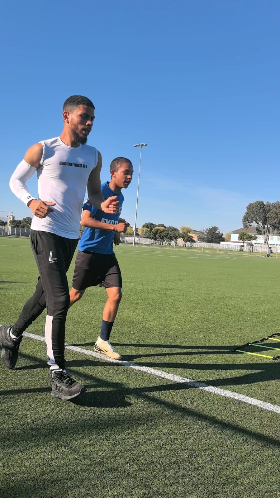 Coach running stride-for-stride with an athlete on the field